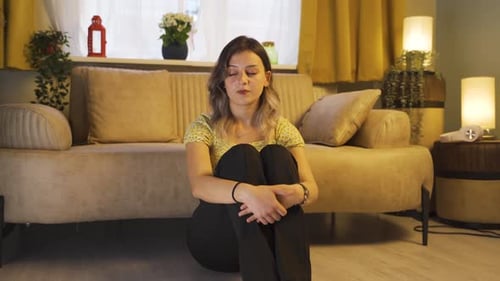 Thoughtful Young Woman Sitting on Floor in Living Room