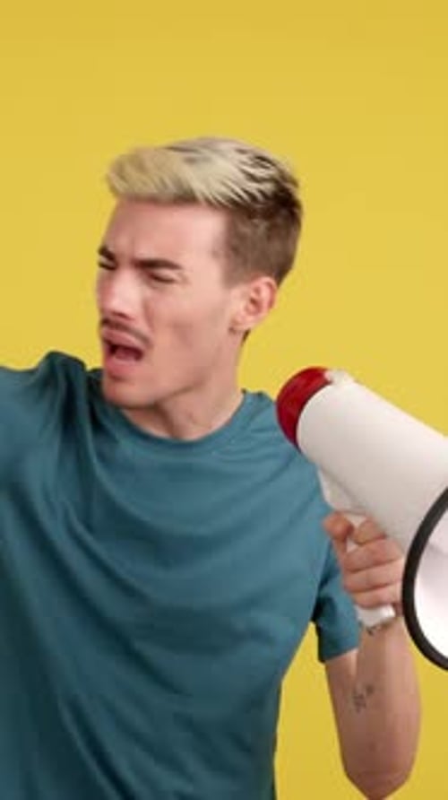 Young Adult Shouting into Megaphone on Yellow Background