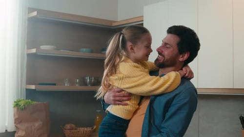 Loving Father Hugs Young Daughter in Kitchen