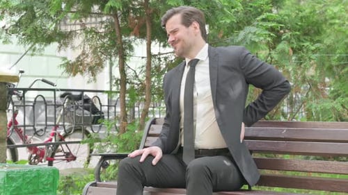 Man Experiencing Back Pain on Park Bench