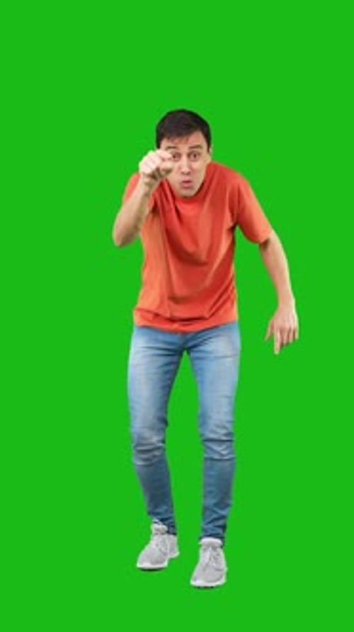 Amazed and Smiling Man Pointing to Front Green Background