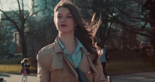 Young Woman Strolling in Urban Park on Windy Day
