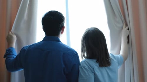 Man and Child Open Curtains at Window