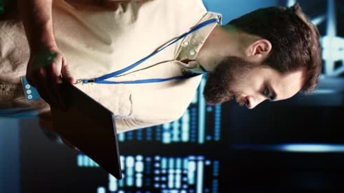 Adult Holding Tablet in Front of Computer Screens