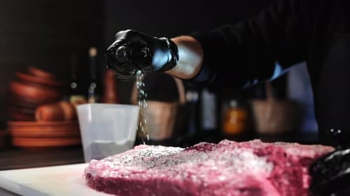 Man Chef Hand Sprinkling Salt Dry Seasonings to Farm Meat Piece at Rustic Restaurant Kitchen Closeup