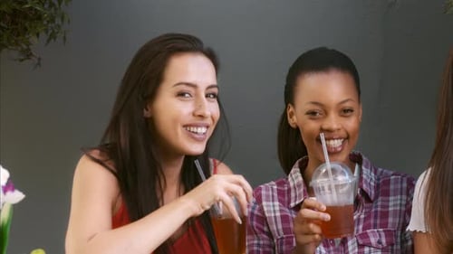Laughing Young Women Enjoying Beverages Together Outdoors