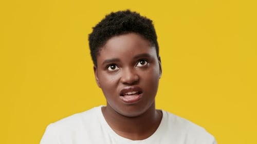 Young Woman Rolls Eyes Against Yellow Background