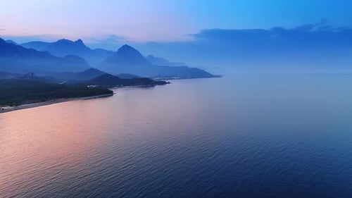 Pink light coloring the waterscape of the seascape at sunset time.
