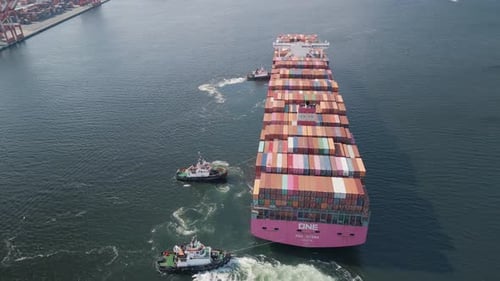 Aerial View of a Large Loaded Container Ship Being Towed By Tugs Into Port