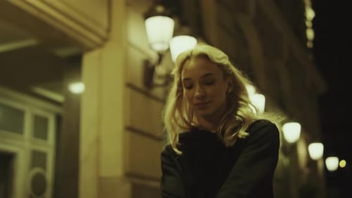Mysterious young woman walking alone at late night in modern city street lights
