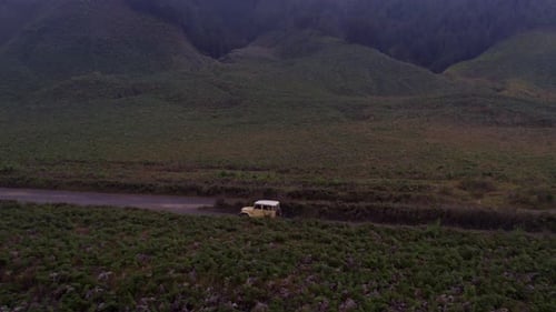 Luftaufnahme von Bromo mit Jeeps auf staubiger Straße, Indonesien.
