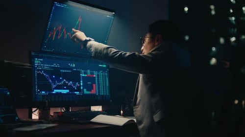 Professional stock trader analyzing financial market charts on multiple monitors