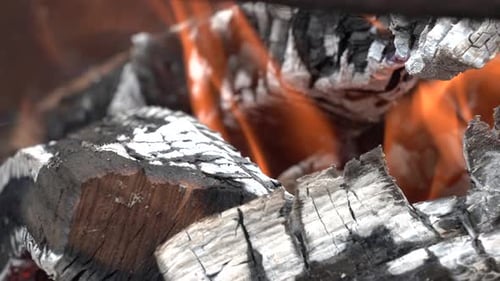 The flames of a fire in a fire pit burning the wood in the campfire.