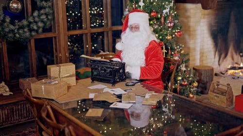 Santa Typing Letters at Desk Near Christmas Tree