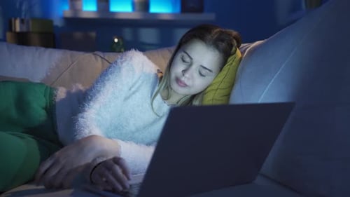Woman Using Laptop While Lying on Couch