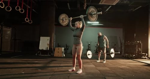 Athletes Doing Clean and Jerk Weightlifting Exercise in Gym