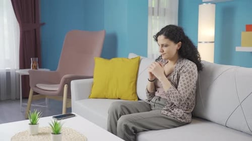 Worried Woman Sits on Sofa in Living Room