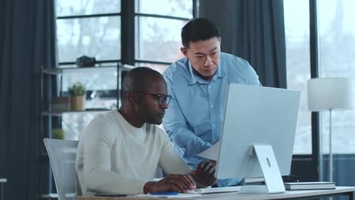 Two Men Collaborate at Computer in Office