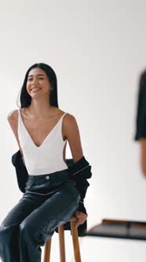 Jeune mannequin posant sur un tabouret en blanc Studio Vertical