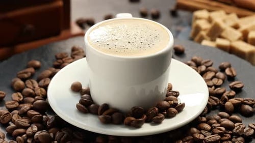 Café aromatique dans une tasse et grains sur la table, gros plan