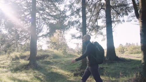 Side View of a Man Tourist with Backpack Hiking Along the Trail in the Forest