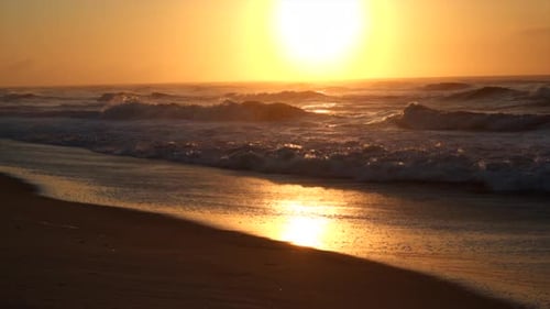 Slow motion clip of sunrise at beach with waves crashing on shore. Long Island New York.