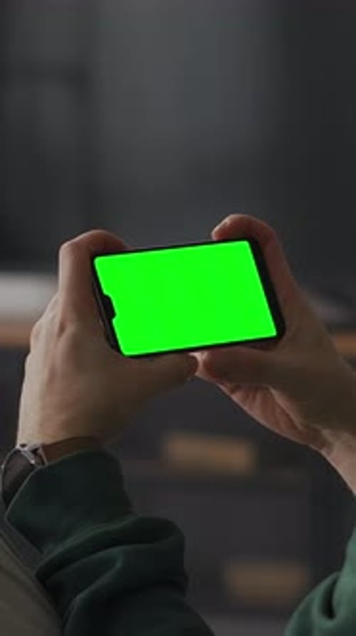 Person Holding Smartphone with Vivid Green Chroma Key Screen in Horizontal Orientation Ready for