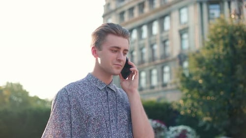 Young Caucasian Man Walking in City and Talking on Smartphone Joyful Caucasian Male Use Smartphone