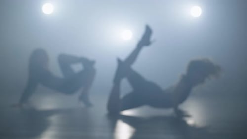 Two Women Dance in Foggy Studio with Dramatic Lighting
