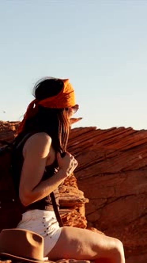 Young female hiker admiring horseshoe bend at sunset