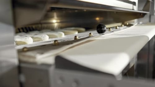 Nahaufnahme von Brotteig, der in den Ofen gestellt wird, um darin frische Baguettes zu backen, die in der Bäckerei zubereitet werden
