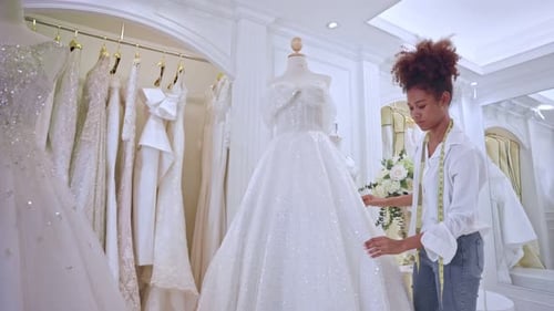 African American female designer designing bridal gown in wedding studio.