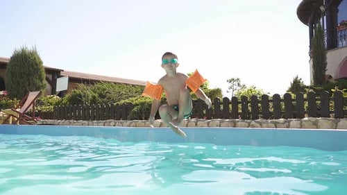 Happy Boy Jumps Into the Pool on a Sunny Day