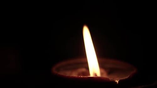 Earthen Diya Lamp Flame Burns in Darkness