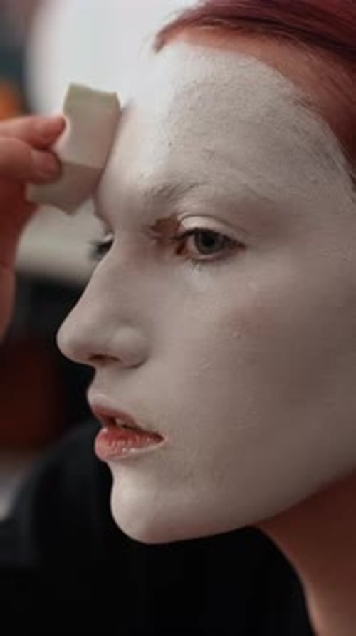Close-up of Young Female Makeup Artist Blending White Face Paint with Sponge