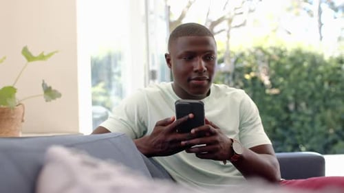 Man Using Smartphone, Makes a Call on Couch