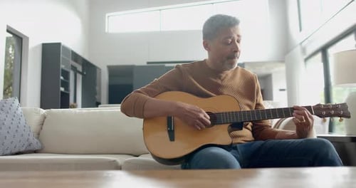 Man Playing Acoustic Guitar on Cream Couch