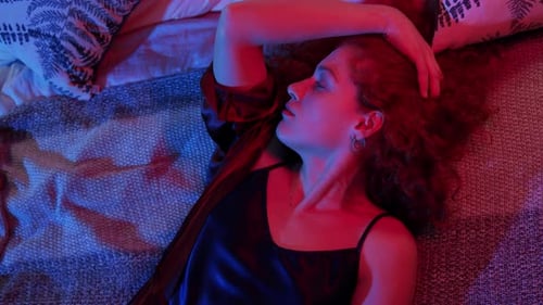 Woman with Curly Hair Lying on Bed at Night