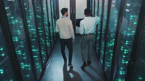 Two Men Navigate a Data Center Discussing Teamwork in Tech