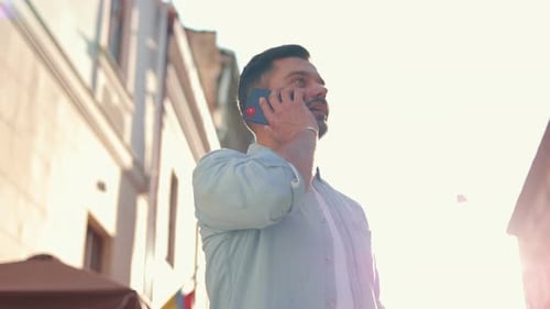 Young Caucasian Man Walking in City and Talking on Smartphone Joyful Caucasian Male Use Smartphone