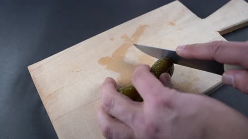 Slicing a Pickle on a Wooden Cutting Board