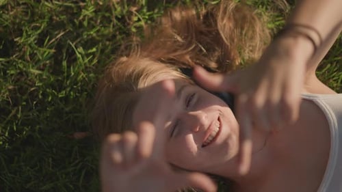 Smiling Woman Lying in Grass Listening to Music