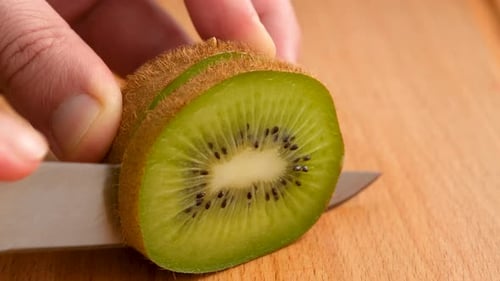 Close-Up View Of Male Hands Cutting Kiwi Fruits On The Kitchen Table