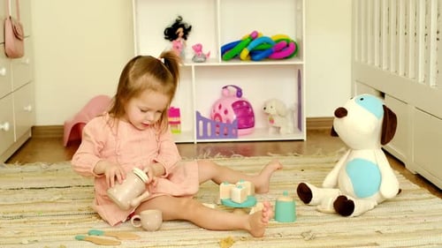 La niña está jugando a tomar té, sirviéndole una bebida a su amiga, un cachorro de peluche de juguete.