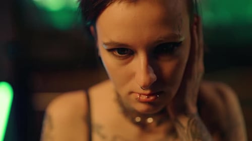 Tattooed Woman with Piercings Touches Face