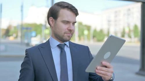 Excited Businessman Receives Good News on Tablet Outdoors