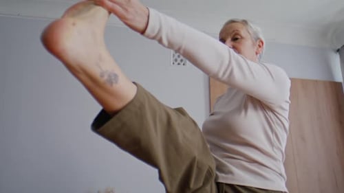 Senior Woman Doing Yoga Stretch in Bright Bedroom