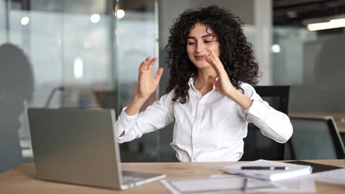 Businesswoman Stretching at Her Desk in a Modern Office