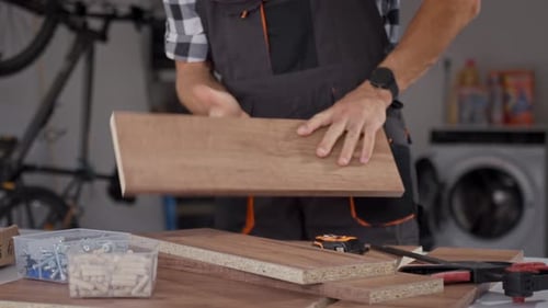Man assembling wooden furniture, measuring board with tape measure