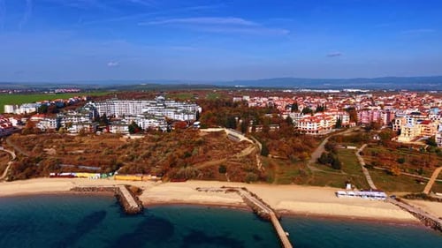 Approaching sandy beach with several piers. Aerial perspective on the modern buildings